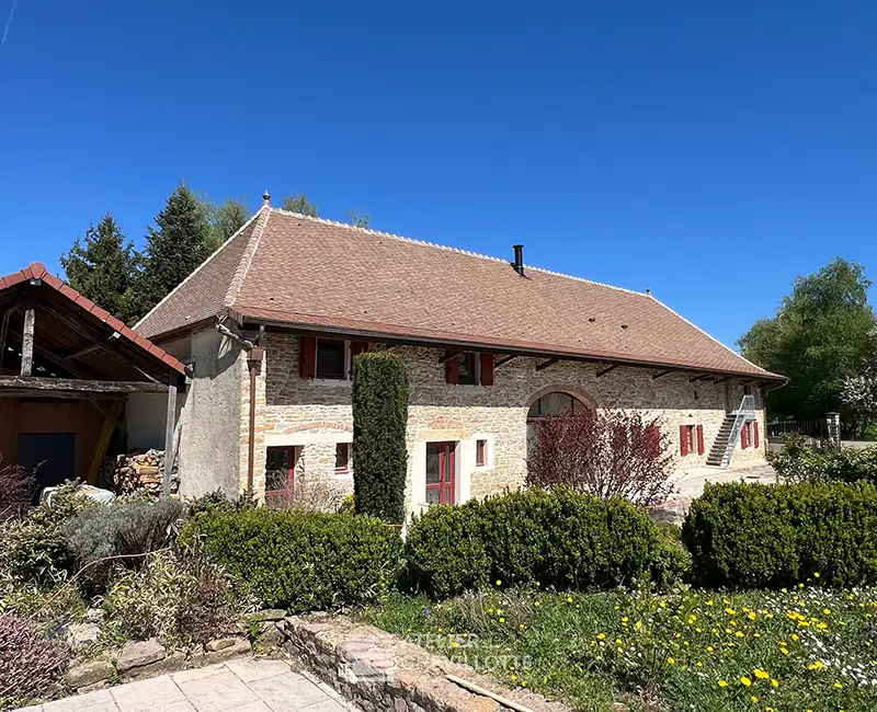 Bâtisse ancienne en pierre réhabilitée avec des ouvertures modernisées et une toiture refaite, illustrant l’adaptation du bâti traditionnel aux usages contemporains.