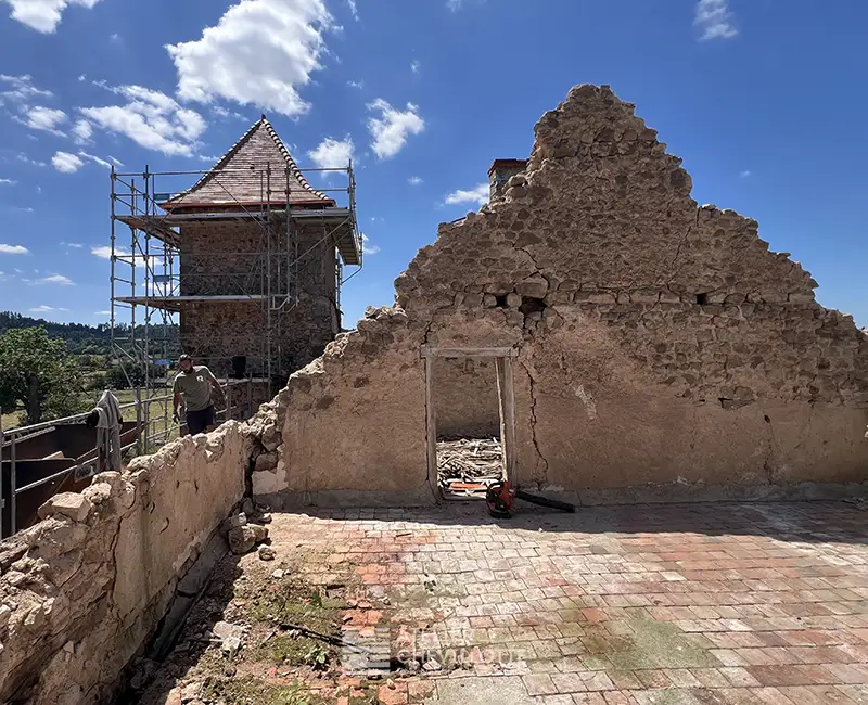 Préservation d’un mur en pierre d’un bâtiment ancien en cours de restauration, avec échafaudage et toiture rénovée en arrière-plan