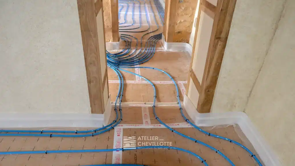 Installation d’un plancher chauffant hydraulique dans une maison ancienne avec réseau de canalisations posées sur isolant polyuréthane avant chape.